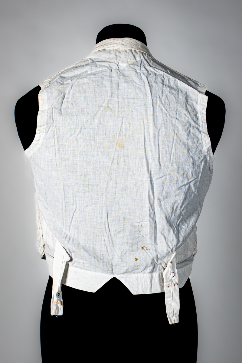 Väst som hör till uniformen som användes av marinläkaren Anders Rudolf Prag.
Anders Prag kom tili Karlskrona 1929 som marinläkare, dispensärläkare och privatpraktiserande läkare, där hans största intresse alltid varit pediatriken, hans huvudintresse och specialitet. Anders Prag har här i staden gjort ett verkligt pionjärarbete i det att han startat barnavårdscentralsverksamheten, om vilken han aven hallit föreläsningar i Karlskrona läkareforening. I föreningen har han varit sekreterare och ordförande. Som marinläkare har Anders nått l:e marinläkargraden. De gåger han underhillit kollegerna med sång till luta, då hans sonora stamma klingat så vackert har varit verkliga högtidsstunder (ur Karlskrona Lakareförening 120 år Från hot om prygelstraff till fastställd arbetstid, SVEN SVENNERUD och HOLGER HOLMGREN 1978). "Gradbeteckningar med olikfärgat kläde mellan galonerna för civilmilitära tjänstemän med specialutbildning inom marinen; rött för marinläkare, vitt för marinintendent och lila för mariningenjör." S. 23 Flottans sjöofficersuniformer i Sjöhistoriska museets samlingar. Nils-Erik Melinder. Sida 38, samma skrift: "Från år 1937, utformades den för sjöofficeraren runda öglan till en rundad triangulär ögla, dessutom poängterad med olikfärgat kläde mellan galonerna. Statusen blev civilmilitär. Ett sammanhängande "öknamn" för den officerskategorin blev därför "päronklubben."