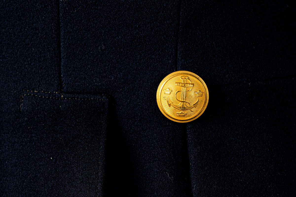 Kappa som hör till uniformen som användes av marinläkaren Anders Rudolf Prag.
Anders Prag kom tili Karlskrona 1929 som marinläkare, dispensärläkare och privatpraktiserande läkare, där hans största intresse alltid varit pediatriken, hans huvudintresse och specialitet. Anders Prag har här i staden gjort ett verkligt pionjärarbete i det att han startat barnavårdscentralsverksamheten, om vilken han aven hallit föreläsningar i Karlskrona läkareforening. I föreningen har han varit sekreterare och ordförande. Som marinläkare har Anders nått l:e marinläkargraden. De gåger han underhillit kollegerna med sång till luta, då hans sonora stamma klingat så vackert har varit verkliga högtidsstunder (ur Karlskrona Lakareförening 120 år Från hot om prygelstraff till fastställd arbetstid, SVEN SVENNERUD och HOLGER HOLMGREN 1978). "Gradbeteckningar med olikfärgat kläde mellan galonerna för civilmilitära tjänstemän med specialutbildning inom marinen; rött för marinläkare, vitt för marinintendent och lila för mariningenjör." S. 23 Flottans sjöofficersuniformer i Sjöhistoriska museets samlingar. Nils-Erik Melinder. Sida 38, samma skrift: "Från år 1937, utformades den för sjöofficeraren runda öglan till en rundad triangulär ögla, dessutom poängterad med olikfärgat kläde mellan galonerna. Statusen blev civilmilitär. Ett sammanhängande "öknamn" för den officerskategorin blev därför "päronklubben."