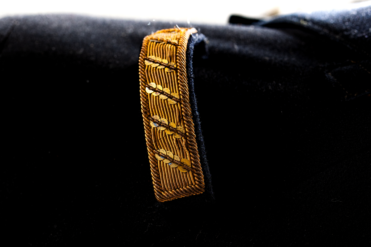 Jacka som hör till uniformen som användes av marinläkaren Anders Rudolf Prag.
Anders Prag kom tili Karlskrona 1929 som marinläkare, dispensärläkare och privatpraktiserande läkare, där hans största intresse alltid varit pediatriken, hans huvudintresse och specialitet. Anders Prag har här i staden gjort ett verkligt pionjärarbete i det att han startat barnavårdscentralsverksamheten, om vilken han aven hallit föreläsningar i Karlskrona läkareforening. I föreningen har han varit sekreterare och ordförande. Som marinläkare har Anders nått l:e marinläkargraden. De gåger han underhillit kollegerna med sång till luta, då hans sonora stamma klingat så vackert har varit verkliga högtidsstunder (ur Karlskrona Lakareförening 120 år Från hot om prygelstraff till fastställd arbetstid, SVEN SVENNERUD och HOLGER HOLMGREN 1978). "Gradbeteckningar med olikfärgat kläde mellan galonerna för civilmilitära tjänstemän med specialutbildning inom marinen; rött för marinläkare, vitt för marinintendent och lila för mariningenjör." S. 23 Flottans sjöofficersuniformer i Sjöhistoriska museets samlingar. Nils-Erik Melinder. Sida 38, samma skrift: "Från år 1937, utformades den för sjöofficeraren runda öglan till en rundad triangulär ögla, dessutom poängterad med olikfärgat kläde mellan galonerna. Statusen blev civilmilitär. Ett sammanhängande "öknamn" för den officerskategorin blev därför "päronklubben."