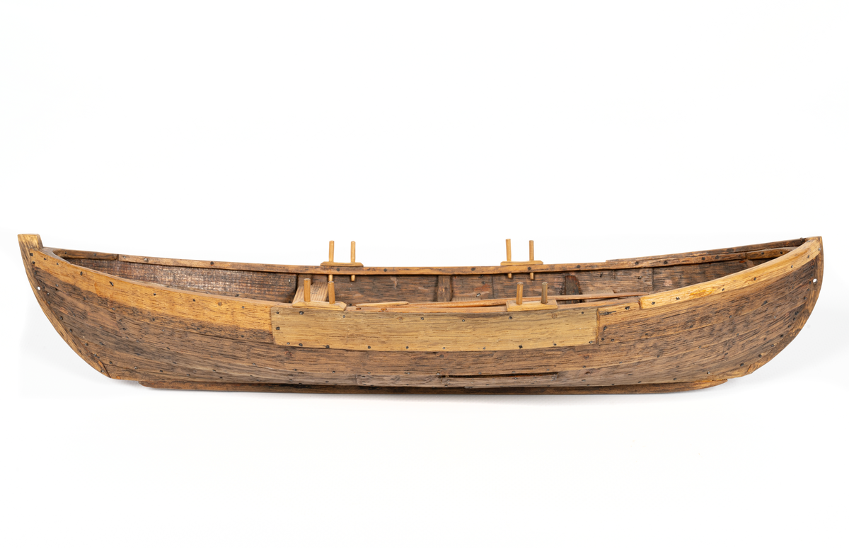Båtmodell, rekonstruerad kopia av Kalmarfynd III, fullt utrustad. Bred kölplanka med stråkköl (ribba under) samt 4 bord på var sida, 3 spant, 4 årlägen för två roddare, 3 tofter, 4 åror.