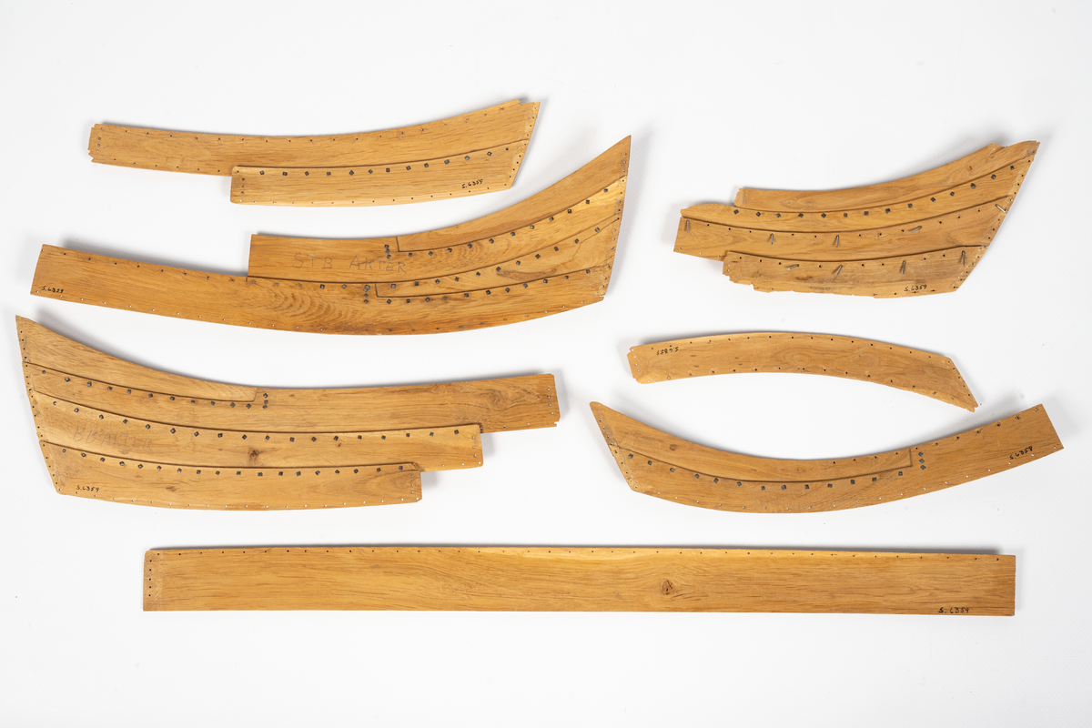 Fartygsmodell av ek, klinkbyggd på spant, högbordigt skepp (knarr)  ÄSKEKÄRRSBÅTEN  (fynd år 1933 fr. Göta älv, daterat 700 e. Kr.) Sidoroder på styrbordssidan, bordläggning förhöjd med ett bord i för- och akterskepp, liten back och halvdäck, kort kölsvin med mastspår.