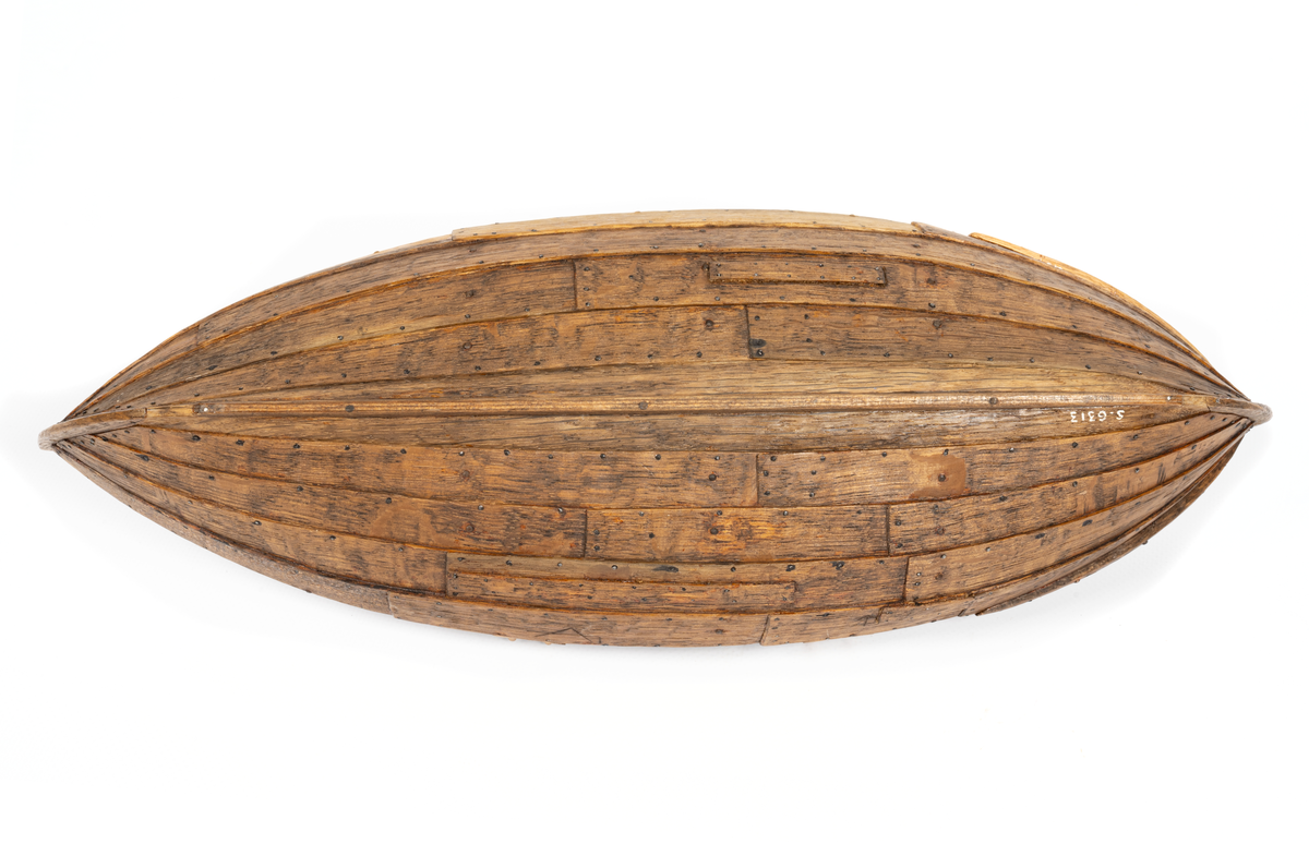 Båtmodell, rekonstruerad kopia av Kalmarfynd III, fullt utrustad. Bred kölplanka med stråkköl (ribba under) samt 4 bord på var sida, 3 spant, 4 årlägen för två roddare, 3 tofter, 4 åror.