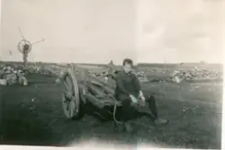 Ein gut sit på ei stor kjerre med to hjul. Vindmaskin og ste