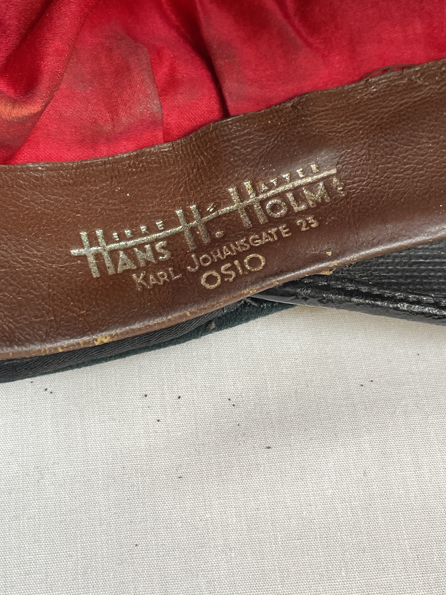 Rittmesterlue, førkrigsmodell, kaptein i kavaleri. Grønn med rødt for. Sølvstriper. Merket Hans H. Holm, Kristiania.