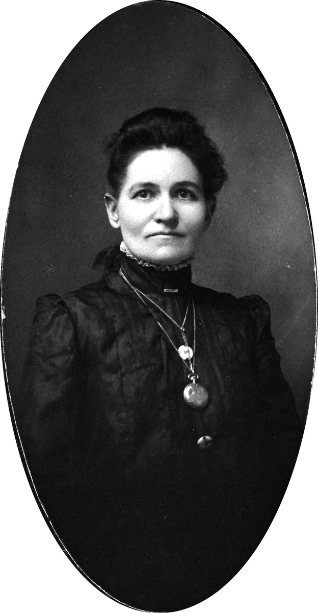 Portrett av en kvinne med mørkt hår og mørk, høyhalset overdel. Rundt halsen har hun en klokke og flere smykker.
Påskrift  bakpå: Emma Kilgore Williams