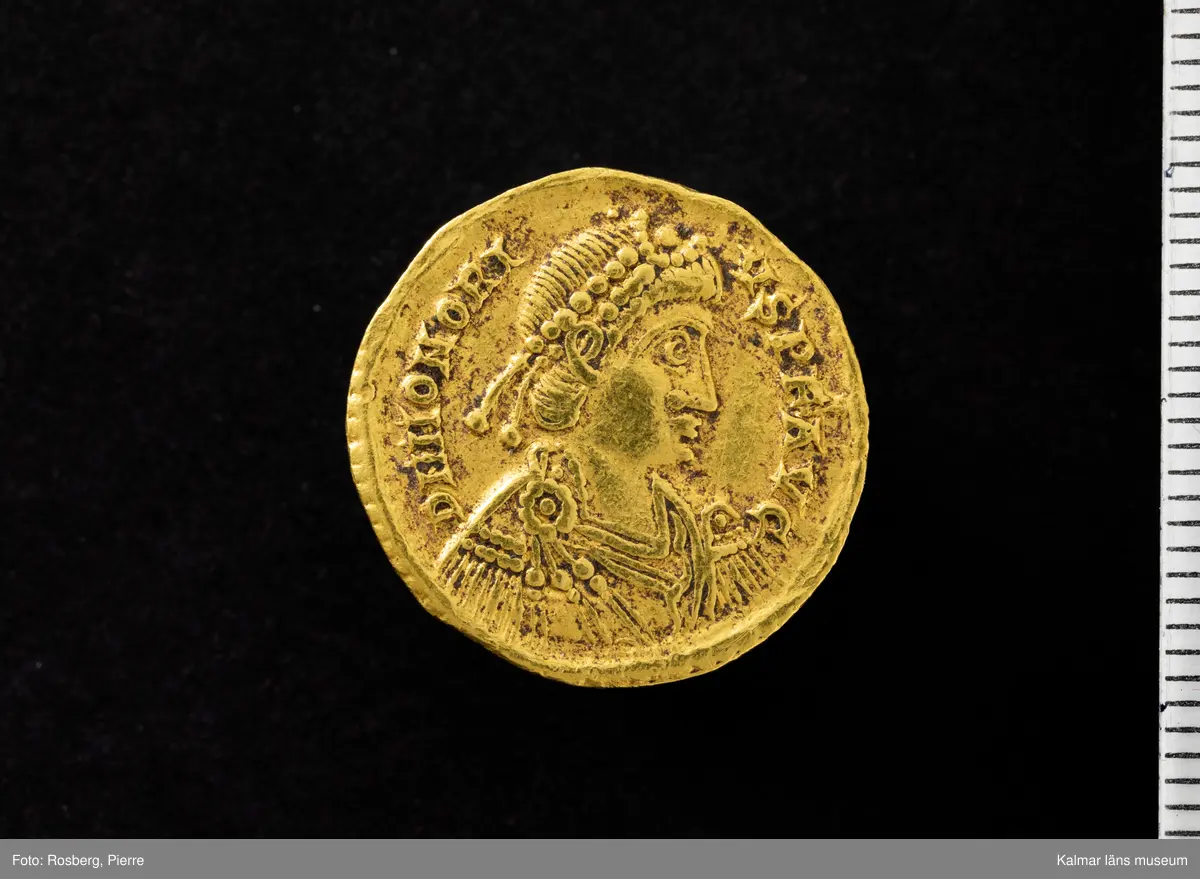 KLM 46712:1. Mynt, solidus. Av guld. Präglad för Honorius (regent 395-423), Ravenna. Åtsida: D N HONORI – VS P F AVG. Frånsida: VICTORI – A AVGGG / R - V. In exergue: COMOB. Bestämning: RIC X 1287. Issued c. 408–423.