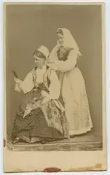 Porträtt på två flickor i folkdräkter från Blekinge.