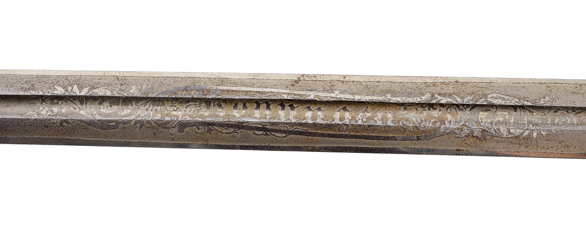 Officerssabel, möjligen modell M 1859 eller M 1899, med förgyllt mässingsfäste. Kaveln är klädd med svärtat fiskskinn, försedd med 8 räfflor lindade med snodd mässingstråd. Ryggbeslaget övergår i en kappa utförd som ett lejonhuvud. Parerplåten är enkelsidig och tillverkad av genombruten förgylld mässing. Klingan är tveeggad, försedd med blodskåror och etsade förgyllda ornament, Smålandsvapnet samt orden "Fäderneslandet" på ena sidan och "Konungen" på andra sidan.

Inskrivet i huvudbok år 1941.