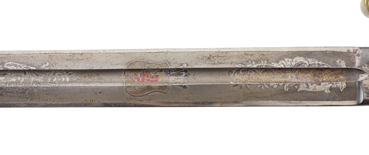 Officerssabel, möjligen modell M 1859 eller M 1899, med förgyllt mässingsfäste. Kaveln är klädd med svärtat fiskskinn, försedd med 8 räfflor lindade med snodd mässingstråd. Ryggbeslaget övergår i en kappa utförd som ett lejonhuvud. Parerplåten är enkelsidig och tillverkad av genombruten förgylld mässing. Klingan är tveeggad, försedd med blodskåror och etsade förgyllda ornament, Smålandsvapnet samt orden "Fäderneslandet" på ena sidan och "Konungen" på andra sidan.

Inskrivet i huvudbok år 1941.