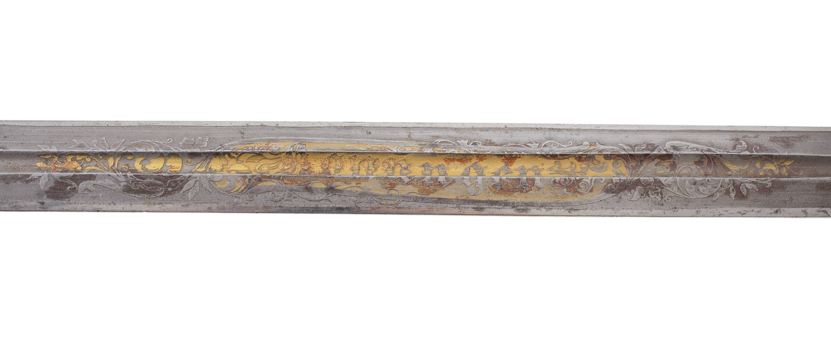 Officerssabel, M1899, med förgyllt mässingsfäste. Kaveln är klädd med svärtat fiskskinn, försedd med 8 räfflor lindade med snodd mässingstråd. Ryggbeslaget övergår i en kappa utformad som ett lejonhuvud. Parerplåten är tillverkad av gjuten mässing, enkelsidig med genombrutet kron- och bladmönster. Klingan är tveeggad, har blodrännor samt dekorationer av blomsterslingor, vapenemblem mm. På ena sidan står "Fäderneslandet" och på andra sidan "Konungen".
Baljan är tillverkad av svärtad plåt och har bygel. 

Inskriven i huvudbok år 1941.