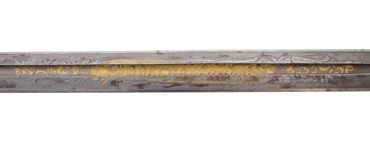 Officerssabel, M1899, med förgyllt mässingsfäste. Kaveln är klädd med svärtat fiskskinn, försedd med 8 räfflor lindade med snodd mässingstråd. Ryggbeslaget övergår i en kappa utformad som ett lejonhuvud. Parerplåten är tillverkad av gjuten mässing, enkelsidig med genombrutet kron- och bladmönster. Klingan är tveeggad, har blodrännor samt dekorationer av blomsterslingor, vapenemblem mm. På ena sidan står "Fäderneslandet" och på andra sidan "Konungen".
Baljan är tillverkad av svärtad plåt och har bygel. 

Inskriven i huvudbok år 1941.