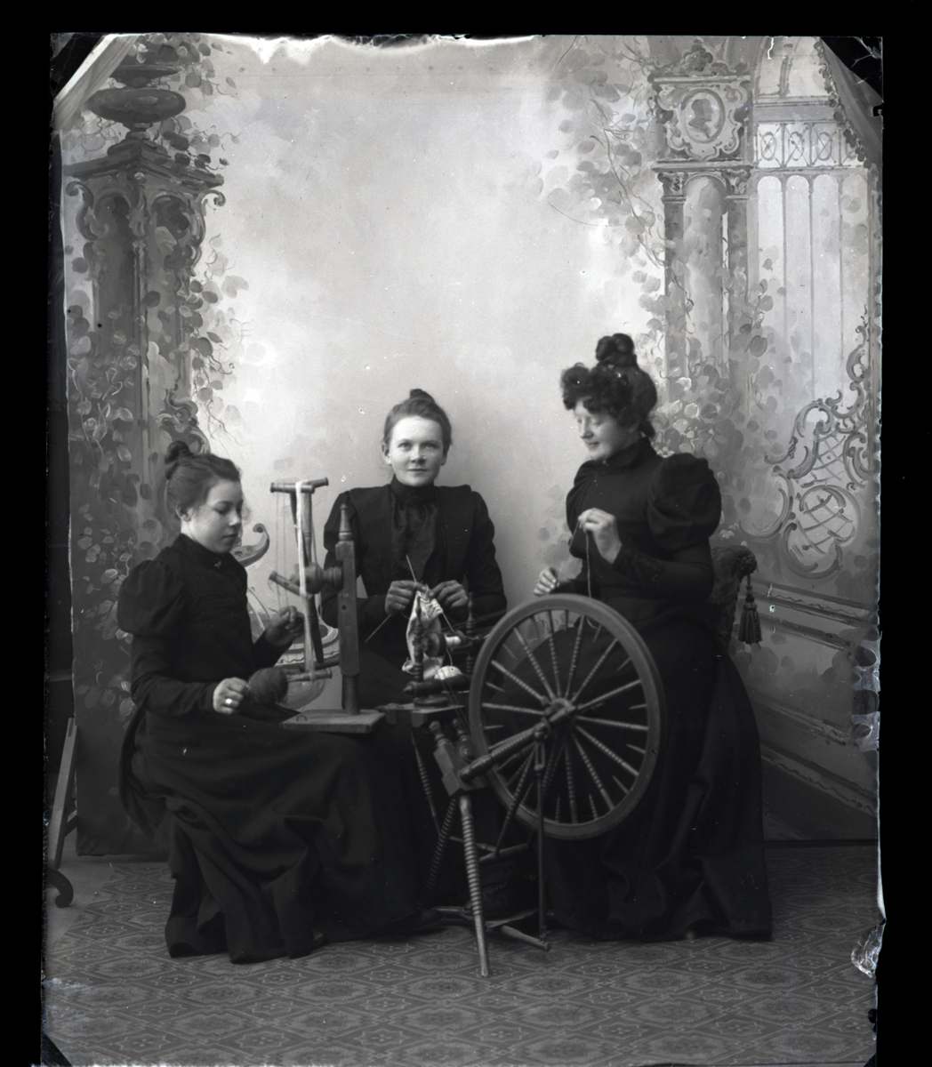 En kvinne og to jenter med rokk og hespetre, en jente strikker.
Skrevet på papir som er festet til negativet: 1080  Gjøvik hotel pigerne (pikene), se bilde GM_MG.03454_1.