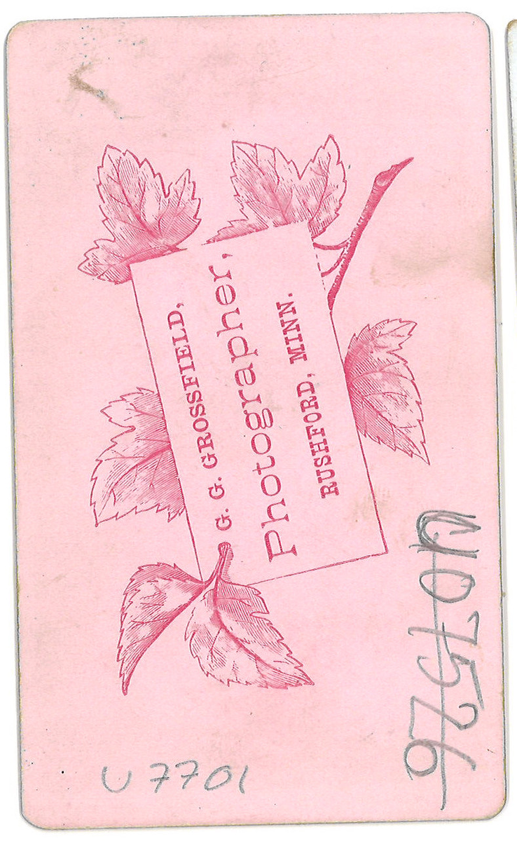 Helfigur studioportrett av en ung kvinne i mørk kjole som lener seg mot en stol.