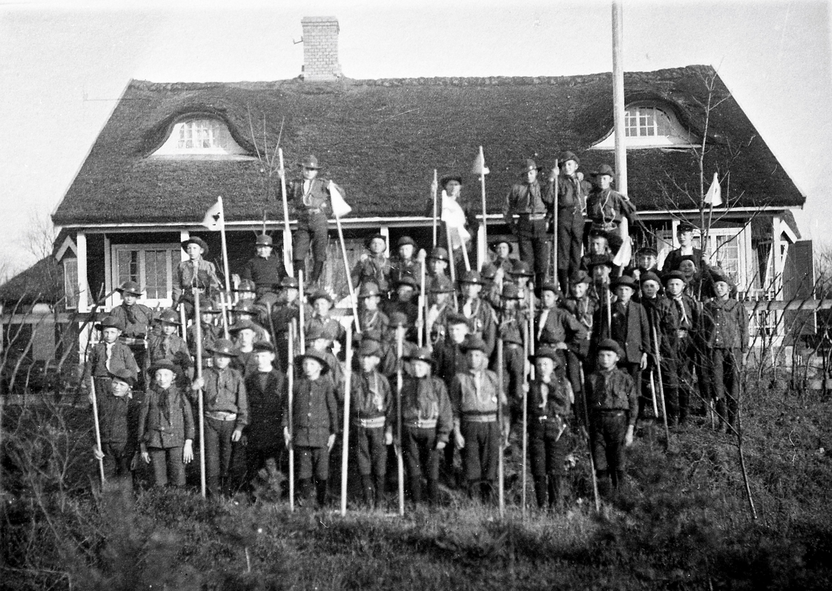 "Tivedstugan+Scoutfest (realskolan+Lambert)". En stor samling pojkscouter har ställt upp sig utanför Tivedstugan år 1918. Där fanns vaktmästarbostad och servering. Senare kom stugan att endast användas som just scoutstuga, tills den brann ner 1954.