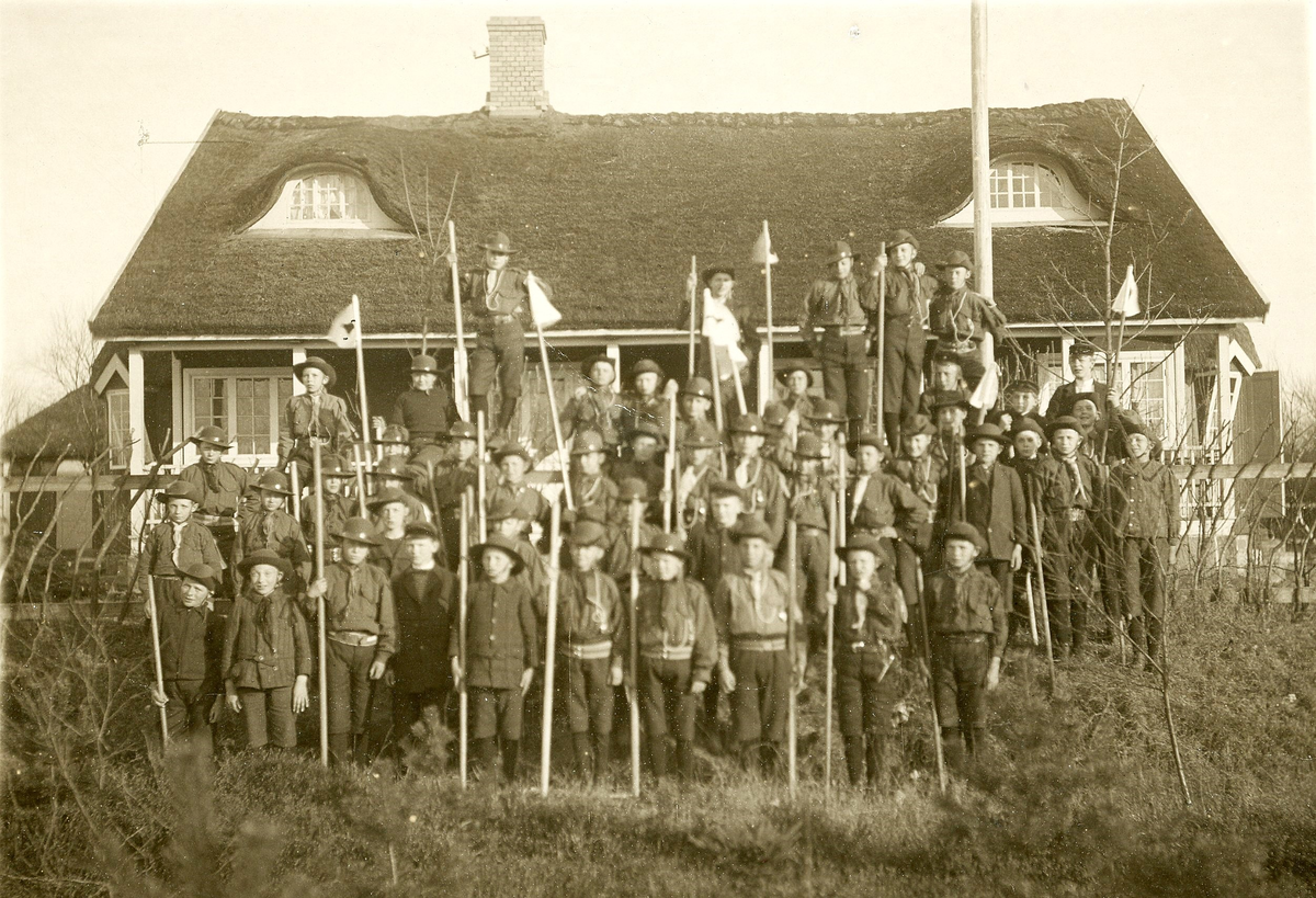 "Tivedstugan+Scoutfest (realskolan+Lambert)". En stor samling pojkscouter har ställt upp sig utanför Tivedstugan år 1918. Där fanns vaktmästarbostad och servering. Senare kom stugan att endast användas som just scoutstuga, tills den brann ner 1954.