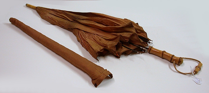 Paraply med tillbehör.
:1 Paraply i metall med bambuhandtag. Smårutigt nylontyg i orange, brunt och beige. Handledssnodd av plastad rundflätad snodd och liten bit bambu som dekoration. 
:2 Fodral i samma tyg som paraplyet. Metallöljett i ena änden och tryckknapp i andra.