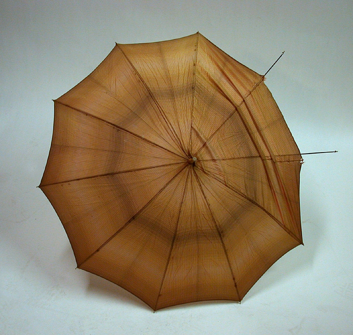 Paraply med tillbehör.
:1 Paraply i metall med bambuhandtag. Smårutigt nylontyg i orange, brunt och beige. Handledssnodd av plastad rundflätad snodd och liten bit bambu som dekoration. 
:2 Fodral i samma tyg som paraplyet. Metallöljett i ena änden och tryckknapp i andra.