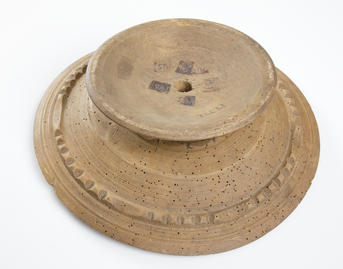 Kakfat av trä, på fot. Skuren dekor på fatets undersida och fot. Fatet är trasigt i ena kanten. Botten glödmärkt "R I. S.".
Inskrivet i huvudkatalog 1886-1887.