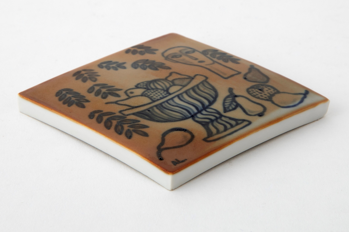 Plakett i porselen. Kvadratisk, noe konveks form. På plaketten et motiv i blå konturtegning på gulbeige bunn. Motivet forestiller et stilleben med stetteskål, frukt, ansikt og fallende løv.