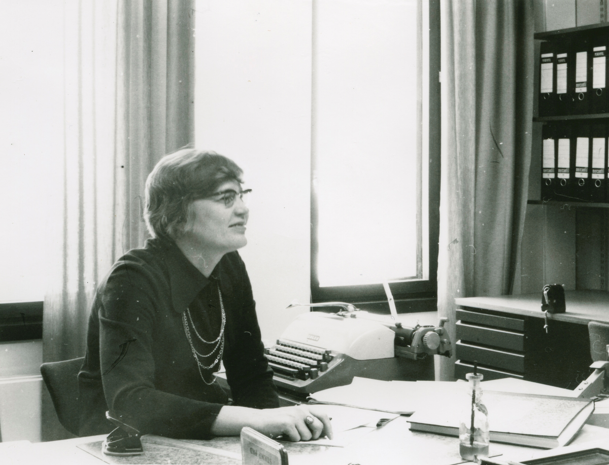 Kvinne ved et skrivebord. Portrett av R. Valkama.