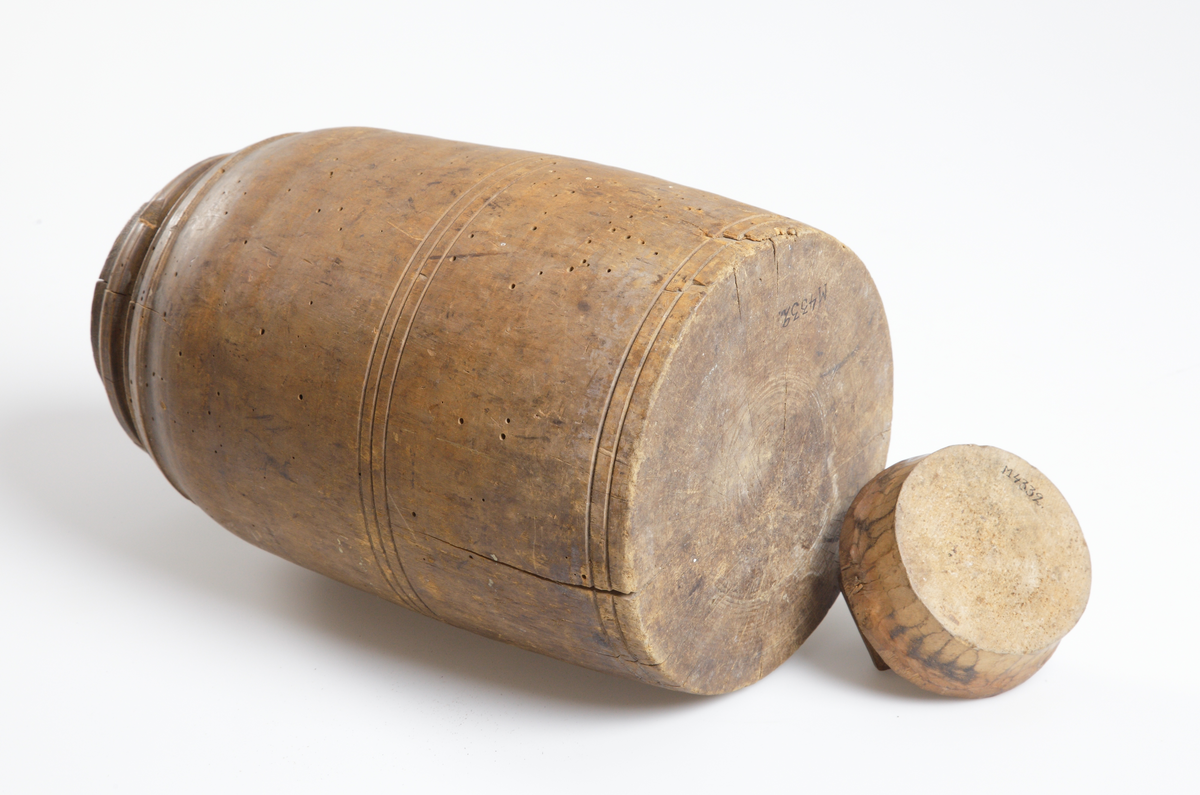 Träurna med lock. Ristade skåror runt urnans mitt- och nedre del.
Inskrivet i huvudkatalog 1928.