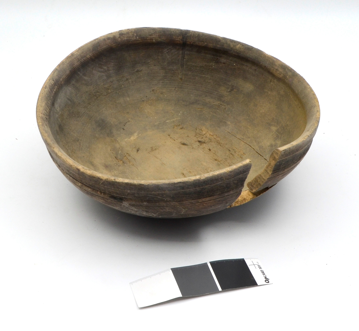 Dreid i furu. Beiset eller oljet. Rund. Profilert kant på utsiden øverst. Kanten fortykket på innsiden. Stor sprekk.