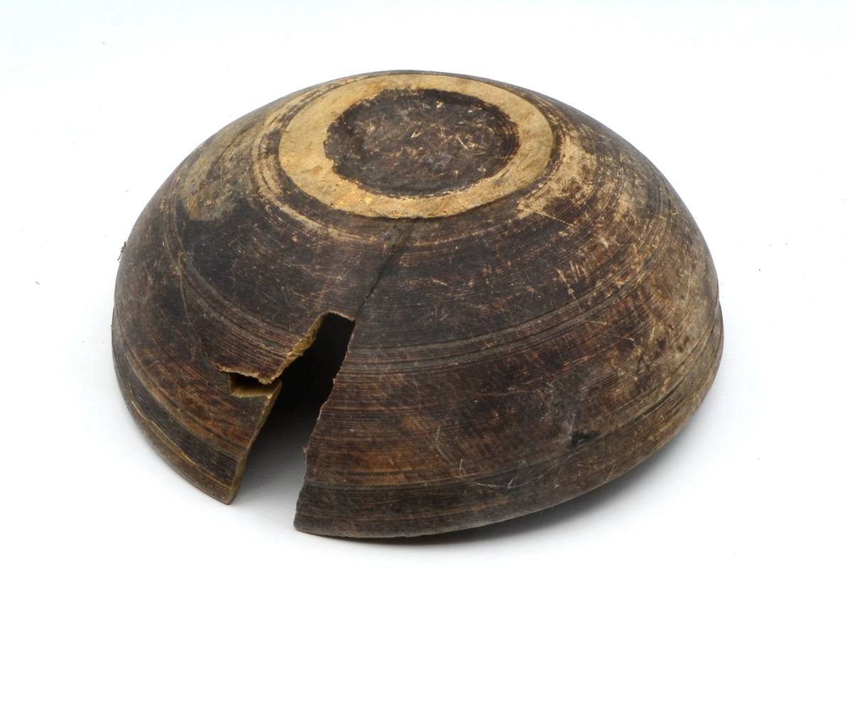 Dreid i furu. Beiset eller oljet. Rund. Profilert kant på utsiden øverst. Kanten fortykket på innsiden. Stor sprekk.