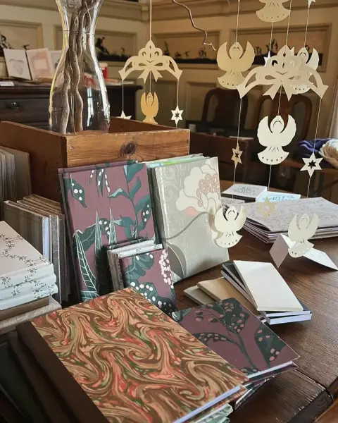 Salgsutstilling med håndlagde bøker og papirfigurer som henger fra taket.