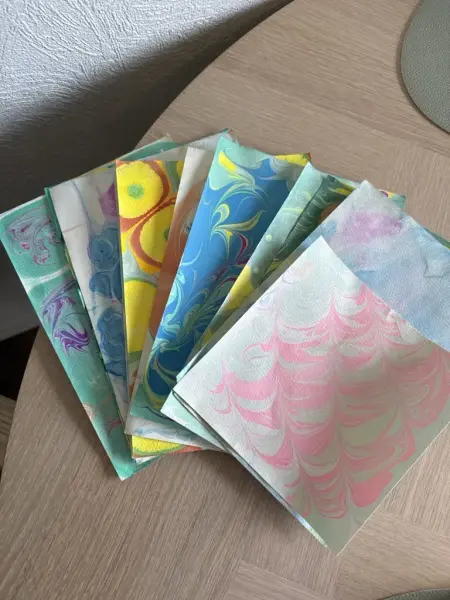 Vi ser flere papirark med ulike farger med marmorering