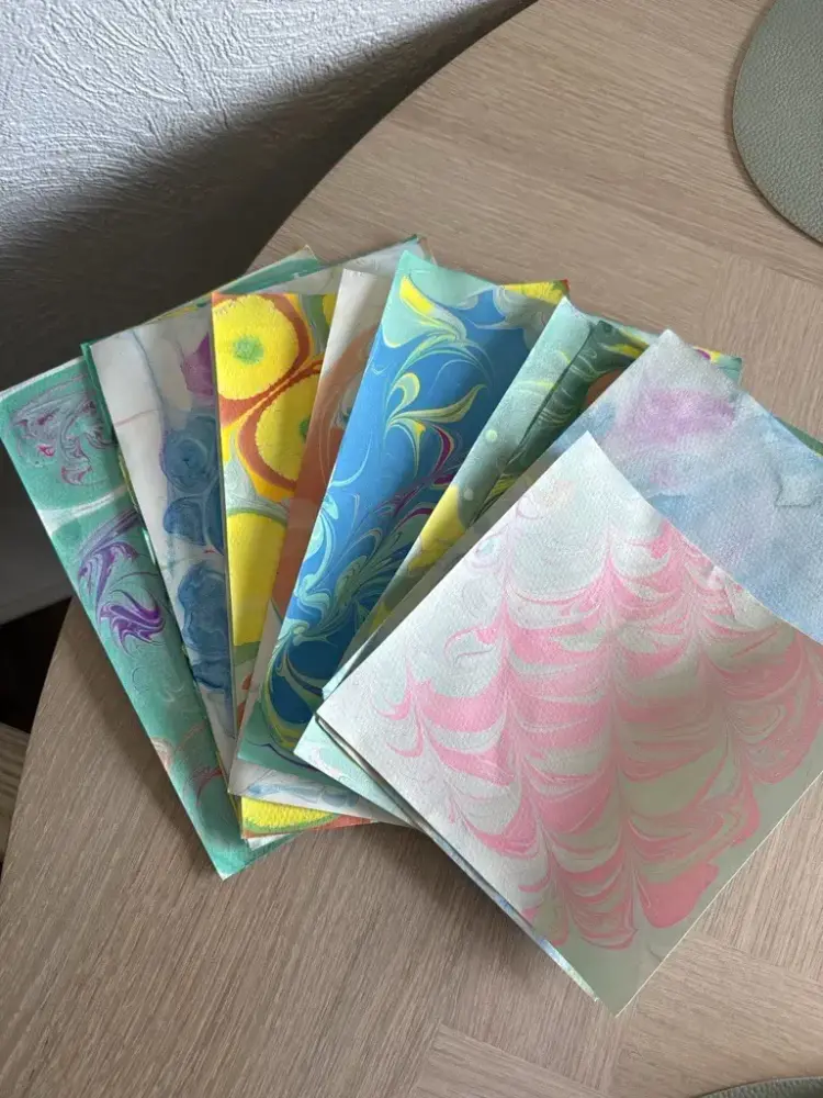 Vi ser flere papirark med ulike farger med marmorering