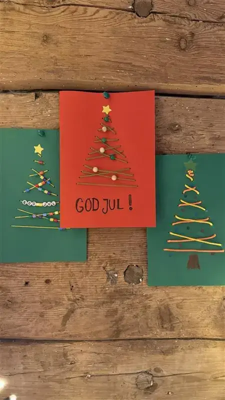Tre fargede julekort, med broderte juletrær på, enkelt laget av barn