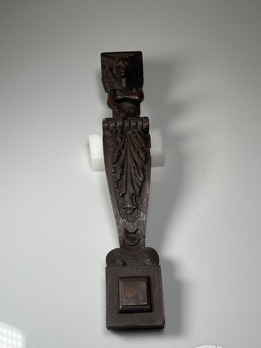 Överkroppen av en ängel på ett pelarformigt postament med bladdekor framtill.
Funktion: Avsedd att hängas på vägg