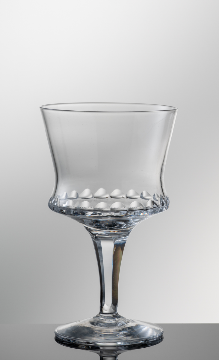 Dessertvinsglas med formblåst kupa, olivslipning runt den nedre valken och påklippt fot och ben med facettslipning.