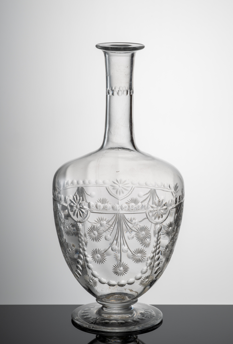 Blommor, bågar, girlanger och oliver. Rand av oliver på halsen, annars mestadels under kupans valk. Syrapolerad blank.