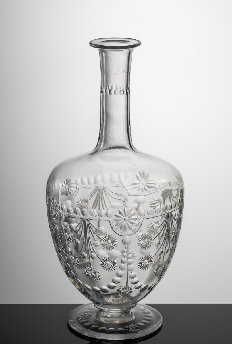 Blommor, bågar, girlanger och oliver. Rand av oliver på halsen, annars mestadels under kupans valk. Syrapolerad blank.