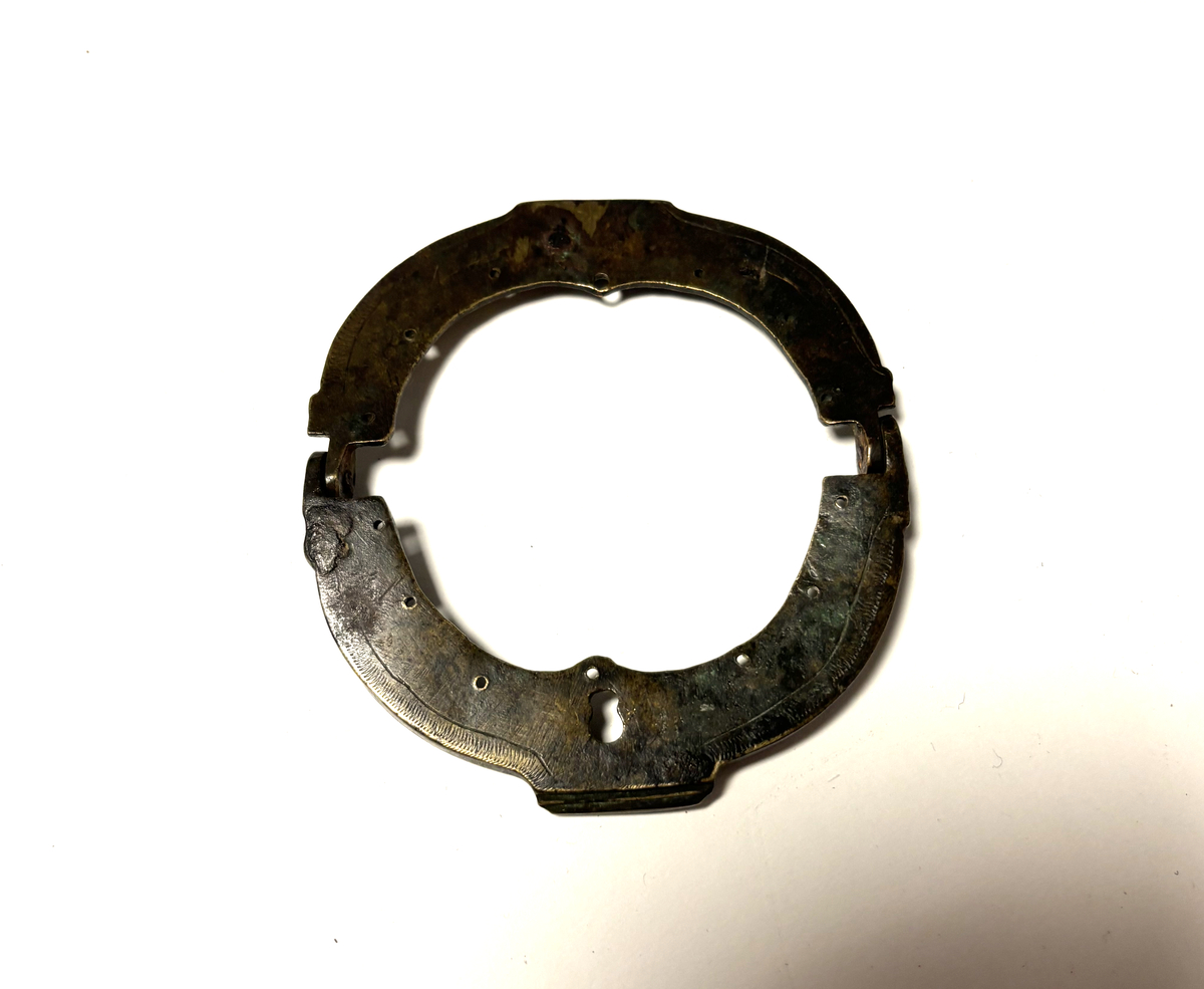 Ovalt, hengsla på midten, festehol langs kanten.