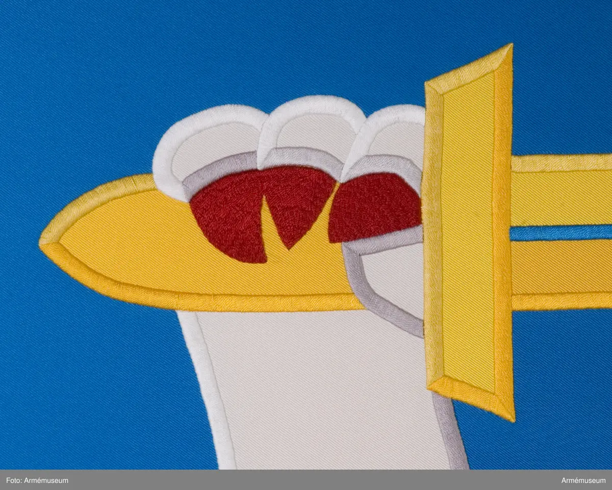 Blå fana med ett vitt lejon med röda och gula detaljer.

Fanduken är tillverkad av blått så kallat fansiden, kypertvävt, med applikationsbroderi i form av ett relativt kantigt framställt vitt lejon hållande ett gult svärd och en gul olivkvist med löv. Lejonet har röda klor och röd tunga.

Fanan är handbroderad med plattsöm, schattérsöm och applikationsbroderi. De gula detaljerna består av applicerat gult fansiden i två olika nyanser medan de röda detaljerna är broderade.

Fanstången är slät och vitmålad. Den nedre halvan mäter 118 cm varav doppskon är ca 11 cm lång och kromad, och skarvdelen av mässing är ca 18 cm.

Fanduken är märkt IB och GF 2007, troligen brodörerna Gertie Frid och Inger Broström.