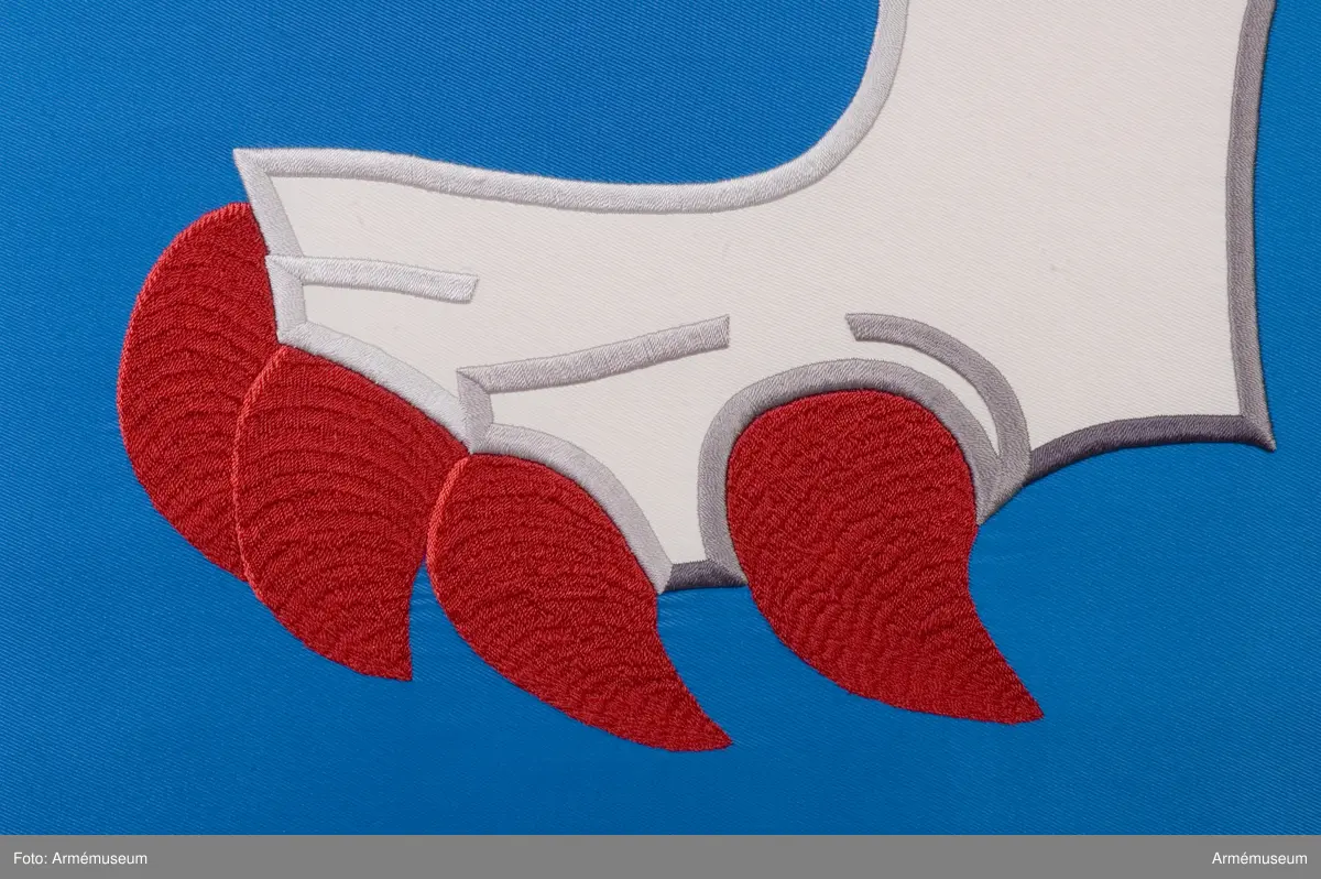 Blå fana med ett vitt lejon med röda och gula detaljer.

Fanduken är tillverkad av blått så kallat fansiden, kypertvävt, med applikationsbroderi i form av ett relativt kantigt framställt vitt lejon hållande ett gult svärd och en gul olivkvist med löv. Lejonet har röda klor och röd tunga.

Fanan är handbroderad med plattsöm, schattérsöm och applikationsbroderi. De gula detaljerna består av applicerat gult fansiden i två olika nyanser medan de röda detaljerna är broderade.

Fanstången är slät och vitmålad. Den nedre halvan mäter 118 cm varav doppskon är ca 11 cm lång och kromad, och skarvdelen av mässing är ca 18 cm.

Fanduken är märkt IB och GF 2007, troligen brodörerna Gertie Frid och Inger Broström.