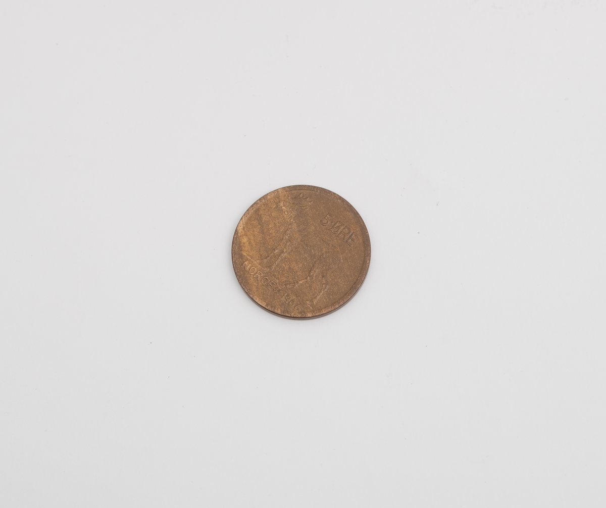 Sparebøsse i metall, med motiv av brennende stearinlys, med en 5 øre i sparebøssen.