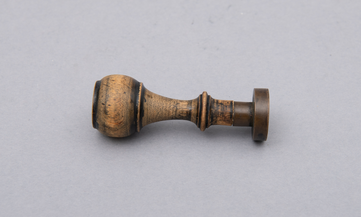 Rundt stempel i messing, med dreiet treskaft.