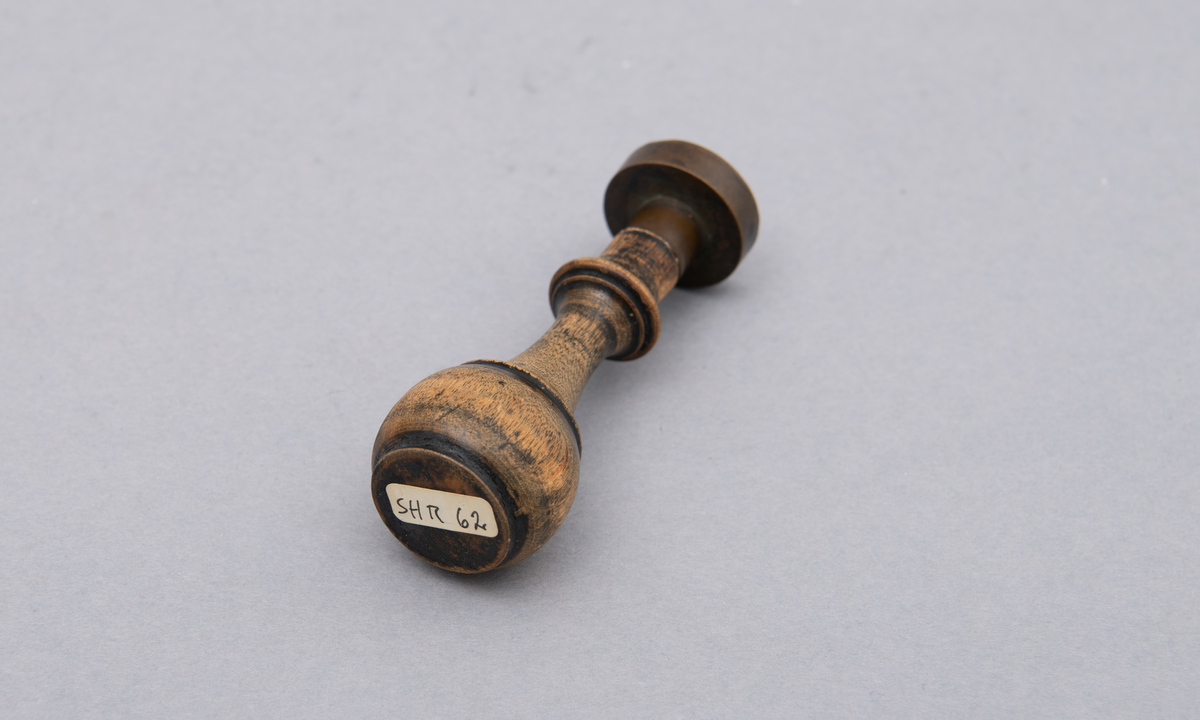 Rundt stempel i messing, med dreiet treskaft.