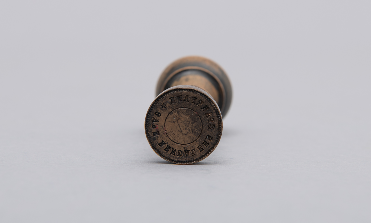Rundt stempel i messing, med dreiet treskaft.