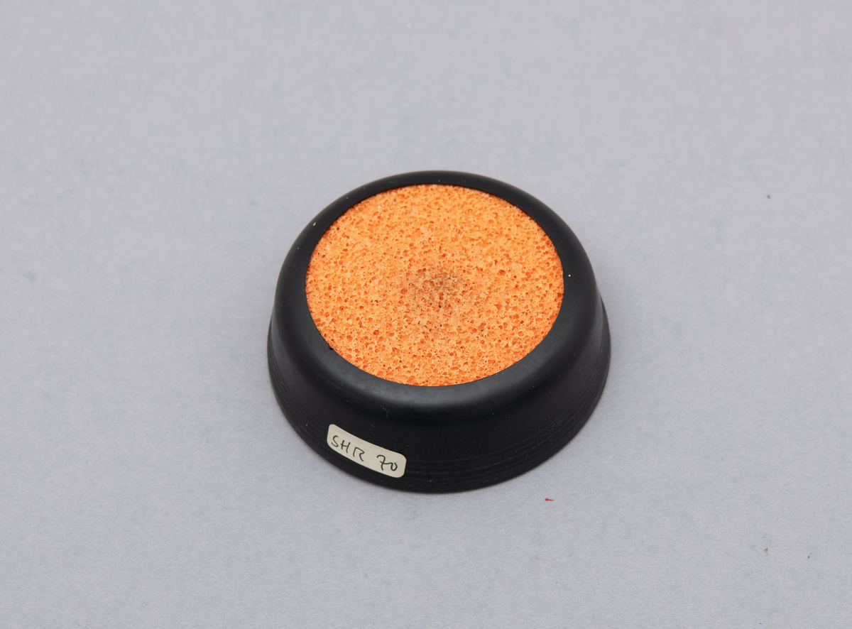 Svamp for fukt av fingre. Holder i svart plast. Oransje svamp av gummi.