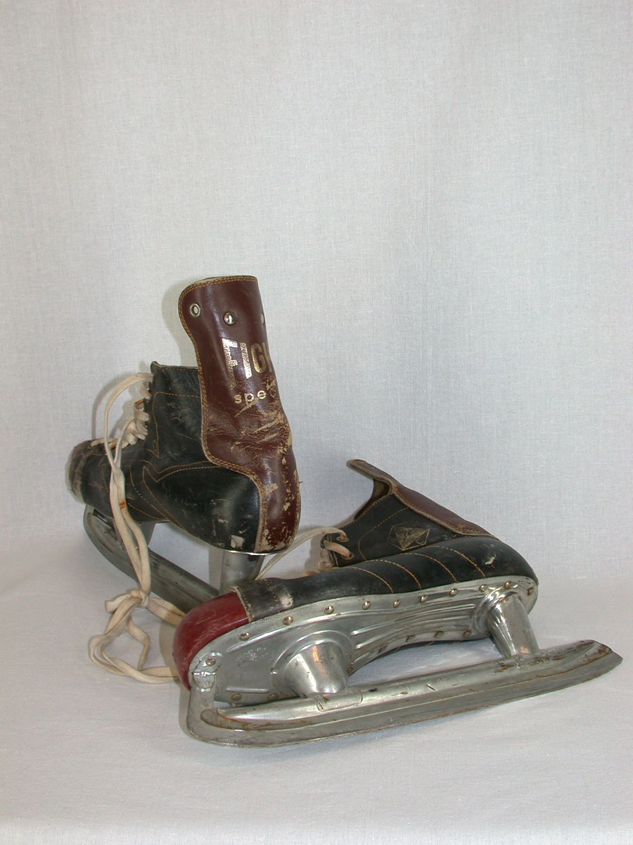 Ishockeyrör
Skon består av svart läder samt brunt läder i tån. På hälen är fastsytt en kappa som är 60 mm högre än skon och 105 mm bred. På yttersulan, under fotenär fastnitat en metallplatta där skenan sitter fast med 50 mm (bak) och 30 mm (fram) höga rör. Snörning med skosnöre i vit bomull som är trädda i nio paralella öljett försedda hål. Vit dekorsöm på ovansidan av foten. På fotens yttersida en sexhörning med konturer i guld innehållande en triangel fylld i guld med svart springande häst med ryttare, mellan sexhörningen och triangeln bokstäverna A B C i guld. Mitt bak på kappan texten Fightspecial i guldbokstäver. Plösen under snörningen i svart skinn fodrad med gukt vadderat tyg. Öljetter som dekor, två överst på  bakkappan och två stycken på var sida snörningen.