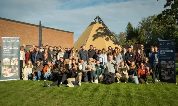 Mange mennesker samlet på en gressplen for å bli tatt bilde av 