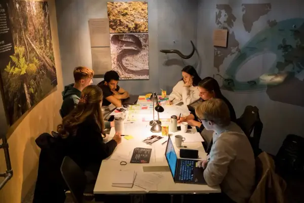 En gruppe elever diskuterer rundt et bord 