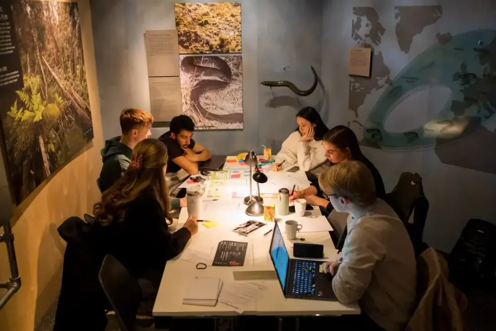 En gruppe elever diskuterer rundt et bord 