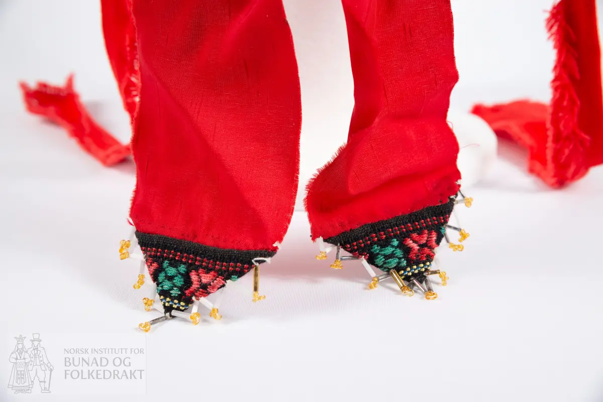 Krone til jonsokbryllup. Perlekrone med trøsk av papp. 
Utsida er dekka med et rødt syntetisk stoff. Innsida er dekka med ubleka bomullslerret, og er polstret med bomullsvatt. Det røde stoffet er perlebrodert, vekselsvis med stjerner og striper. Øverst midt bak er det sydd på to brede, røde bånd av samme stoff som det er festa rundt trøsken.
En liten spiss med mønstrete ullstoff med innvevd blomstermønster er sydd på i enden på hver av båndene, disse er kanta med perler.
Knytebånd av grovt, rødt bomullsbånd. Over trøsken sitter en smal bord med gule perler, deretter er festa et blått syntetisk bånd.
Begge deler støtta opp av spiler, som er dekka med et syntetisk oransje stoff. Øverst er spilene dekka med et hvitt skråbånd. Til øverste kant er festa dusker av ullgarn i rødt, gult og grønt.
Til øverste kant er det festa noen perlefrynser, noen er dekorert med en større rombeforma metallbit i enden, mens andre har en større grønn perle.
Eier har fått opplyst at dette skal stamme fra en gammel lampeskjerm. Krona har også en rad gule perler rett over det blå båndet.
All synlig søm er gjort for hånd.
Produsent laget utstyret sammen med sine barn ca. 1910-1920. Trolig brukt til 1970-åra.