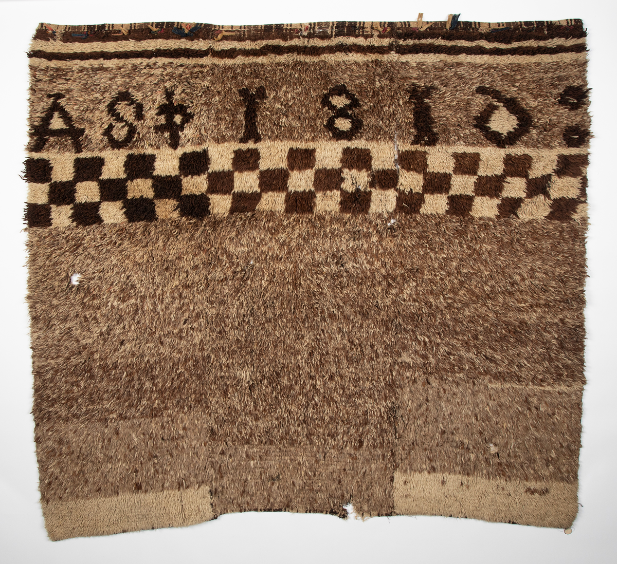 Håndlaget rye i ull, flossteknikk, Bunnen består av treskaftet kyper (stoff vevd med et mønster av skrå linjer), sydd sammen av tre bredder. Fargene er hvitt, sauesvart, brunt og brunmelert. Glattsiden er stripet på langs. På flossiden er det i den ene enden hvite og brune tverrstriper og et felt med brune ruter på hvit bunn (sjakkbrettruter). Mellom disse felt et brunmelert felt hvori initialer og årstall: "A S P  1816". Resten er brunmelert. Stoffdusker øverst i rød, blå og sauehvit ull.