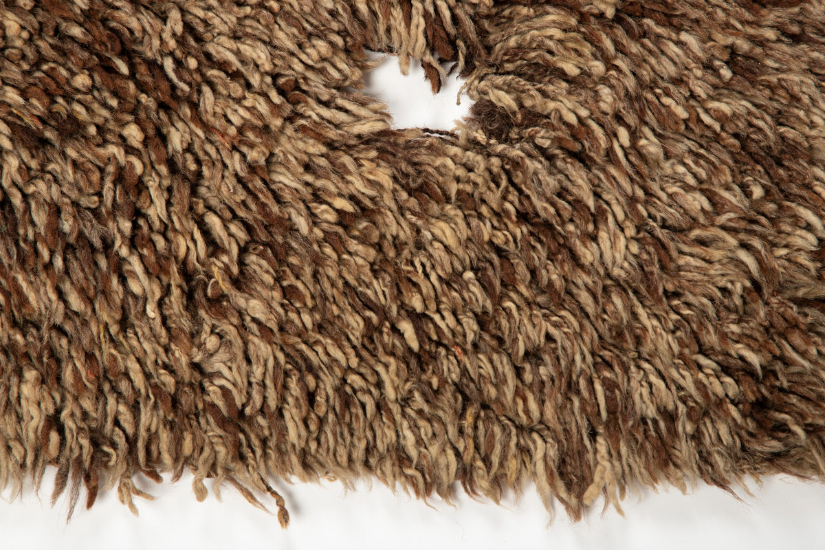 Håndlaget rye i ull, flossteknikk, Bunnen består av treskaftet kyper (stoff vevd med et mønster av skrå linjer), sydd sammen av tre bredder. Fargene er hvitt, sauesvart, brunt og brunmelert. Glattsiden er stripet på langs. På flossiden er det i den ene enden hvite og brune tverrstriper og et felt med brune ruter på hvit bunn (sjakkbrettruter). Mellom disse felt et brunmelert felt hvori initialer og årstall: "A S P  1816". Resten er brunmelert. Stoffdusker øverst i rød, blå og sauehvit ull.